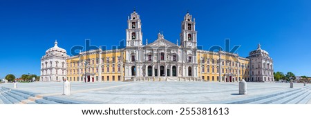 Mafra, Portugal - September 02, 2014: Tourists stroll in front of the Mafra National Palace, Convent and Basilica. Franciscan Religious Order. Baroque architecture.