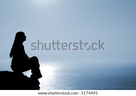 Meditating woman silhouette against seascape.