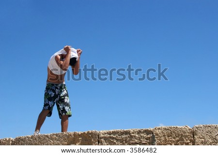 The man removes clothes and prepares for a jump in the sea