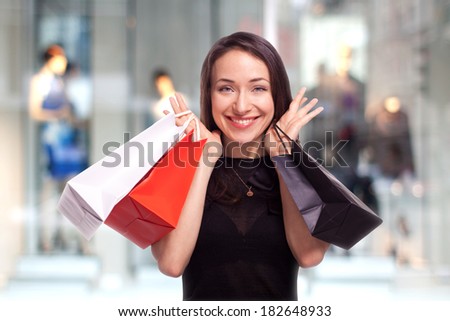 Woman in the shopping center with bags in frot of the showcase with mannequins