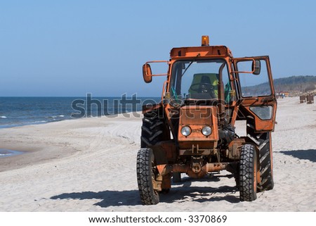 old orange colored tractor on the deserted beach
