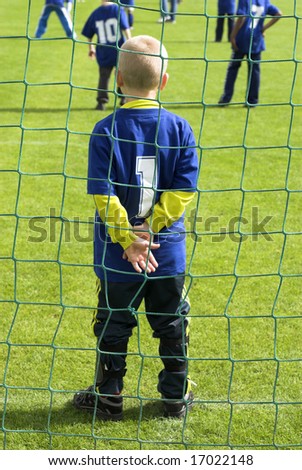 Young football goalkeeper with number one just on the goal line. Focus on the net