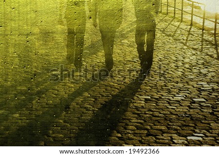 Three men walking in the sun on cobblestone road. Be reflected in gold mirror with raindrops.