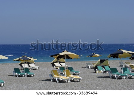 Green, yellow and black parasols and outdoor chairs close to the sea.