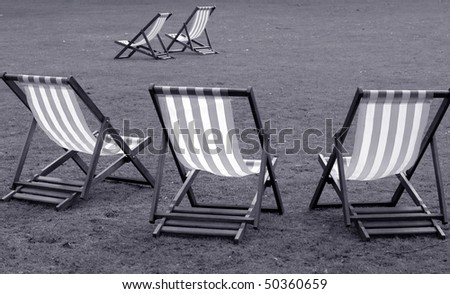 Deck chairs in black and white in London park.