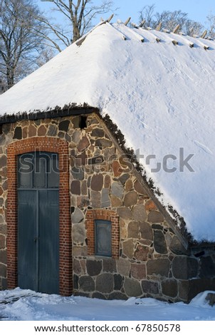 Danish vintage building with thatched roof and covered with snow.