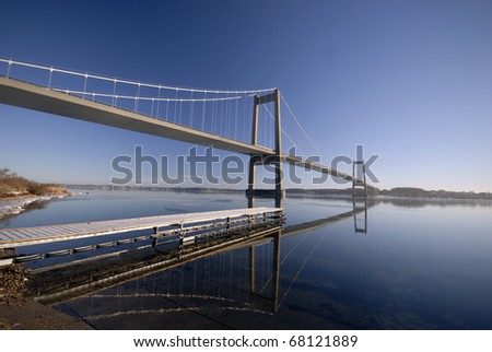 Beautiful suspension bridge close to frosty wooden bridge a cold blue day in Denmark.