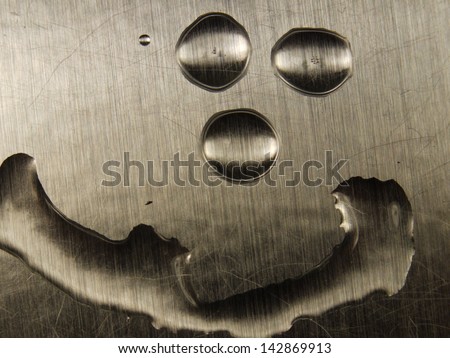 Smiley face formed of water droplets on sheet metal background.