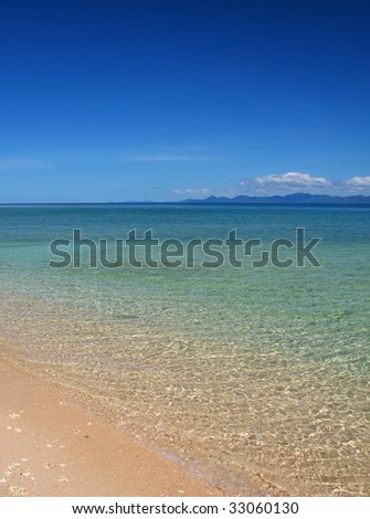Clear waters of a beautiful coral beach with clear blue sky.