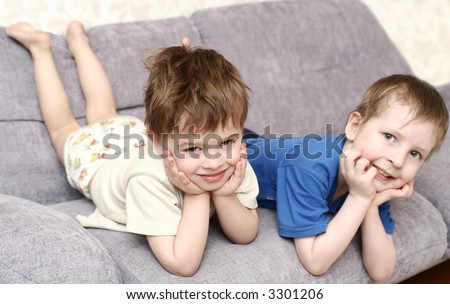 Two boys lay on a sofa together