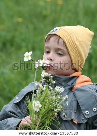 The boy smells a bouquet of flowers in the afternoon