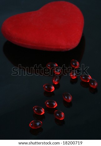 Many red tablets on a black background and red heart