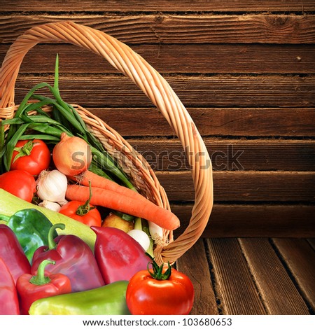 Fresh vegetables in a woven basket on wooded background