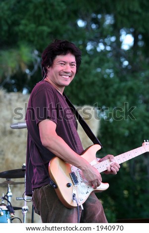 Asian blues singer and guitarist performing during an outdoor concert