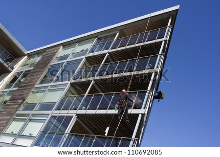 Window cleaners hanging in their ropes washing windows in a modern waterfront apartment house.