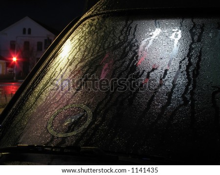 Wet front screen of parked car in the night.