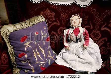 Antique and worn rag doll sitting in old sofa.