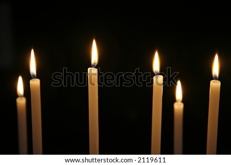 Candles in Roman Catholic church. Focus on flame number three from left. Natural lightening.