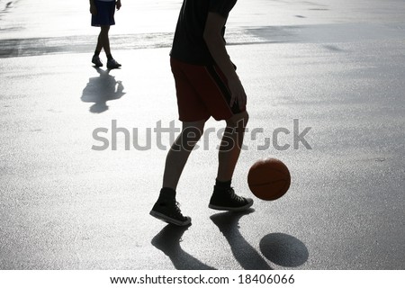 Teenagers playing in the street with a basketball just after the rain.