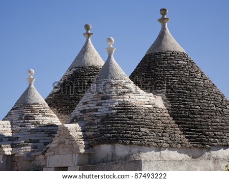 The roof of a rural trullo villa against a blue sky - Italy. A trullo is a traditional Apulian stone dwelling with a conical roof. The style of construction is specific to Itria Valley.