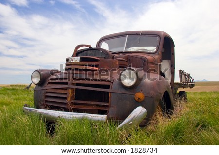 A rusty old pickup truck sits derelict in a field