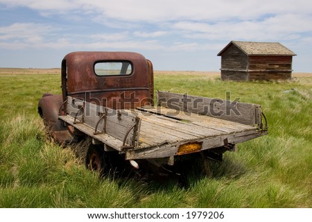 stock photo A rusty old pickup truck and shed in a field