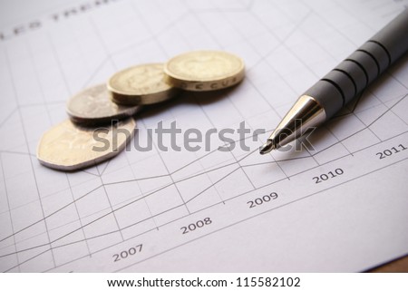 Pen and coins on Financial Chart with positive growth pattern