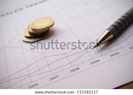 Pen and coins on Financial Chart with positive growth pattern