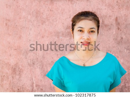 The woman is smiling, and pink walls