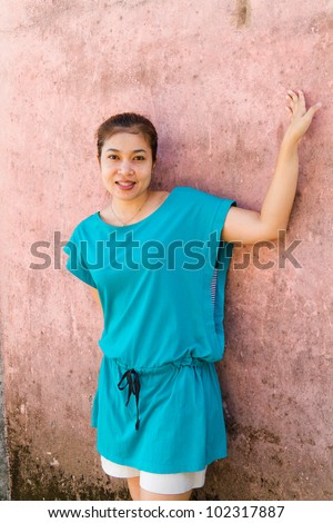 The woman is smiling, and pink walls