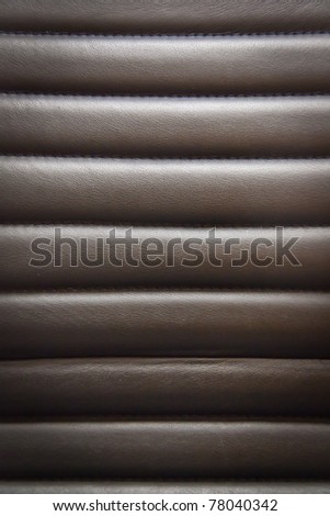 Black leather seats are welded to horizontal suture background texture