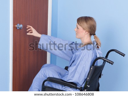 A disabled person struggling to open a door by themself