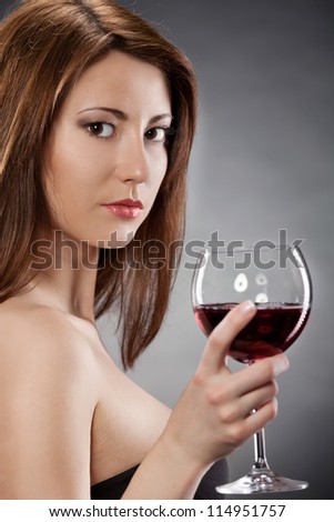 Young woman with glass of red wine.Dark background.