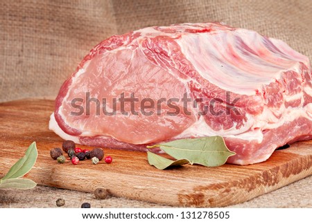fresh raw  pork loin with bay leaf on wooden board and on the background of sacking