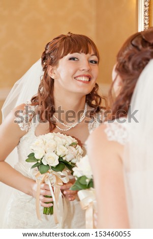 Beautiful bride  looking through mirror and smiling