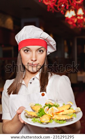 Young attractive chef showing plate of stuffed clams with cheese, herbs and lemon.