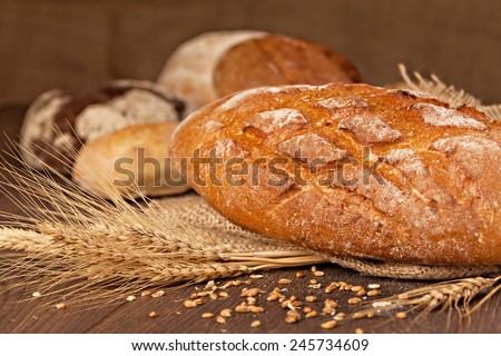 An assortment of freshly baked breads on wooden table. Shallow depth of field.