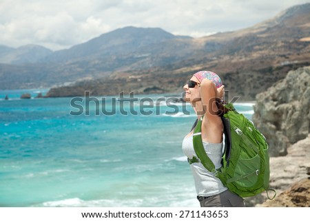 Female tourist with backpack by the coast of sea enjoying journey