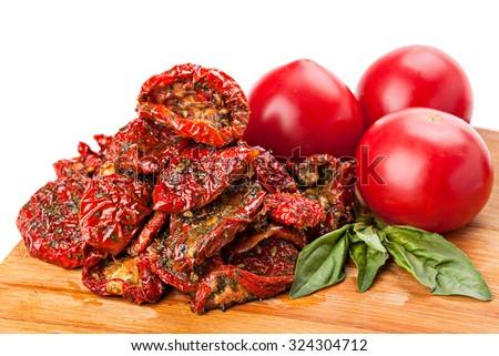 Heap of sun dried tomatoes with basil leaves and fresh ripe tomatoes, isolated on white background.Studio shot.