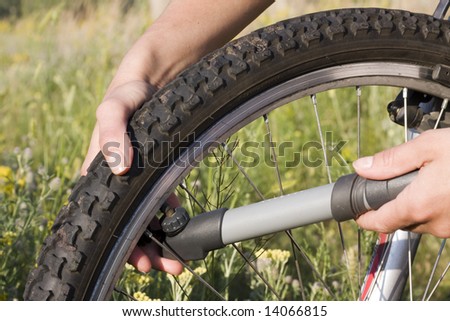 Inflating the tire of a bicycle in the grass meadow