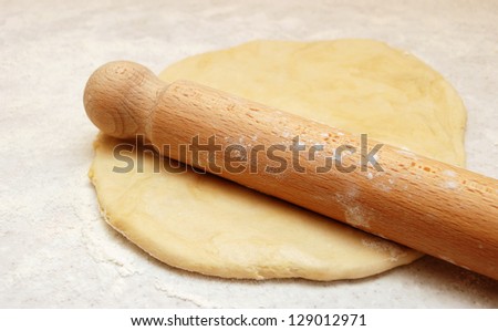 Wooden rolling pin, ready to roll out fresh pastry on a floured surface