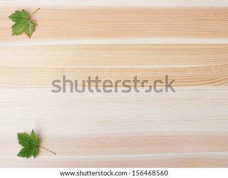 Two green sycamore leaves on a wooden background with copy space