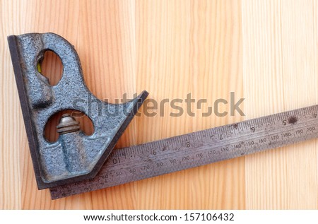 Closeup of metal set square on a wood grain background