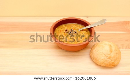 Seasoned lentil soup ready to eat with a crusty bread roll with copy space