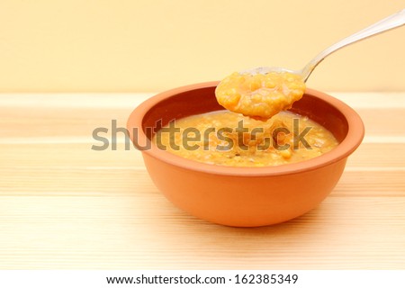 Closeup of spoonful of hearty lentil and vegetable soup lifted from the bowl