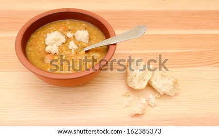 Thick lentil soup dotted with pieces of crusty bread roll