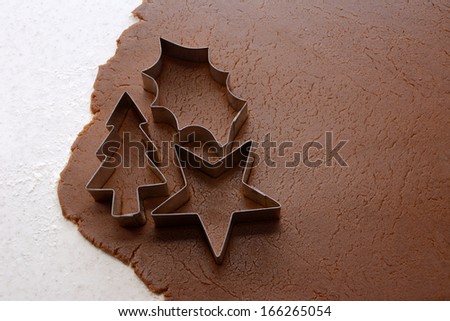 Cutting out Christmas tree, holly leaf and star shapes from gingerbread dough