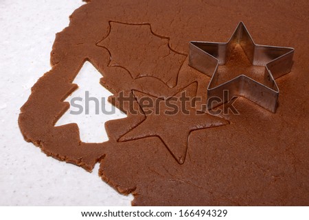 Festive shapes and star cookie cutter on gingerbread cookie dough