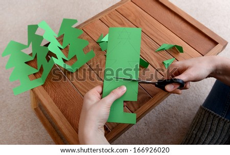 Woman cutting out a paper Christmas tree chain with scissors