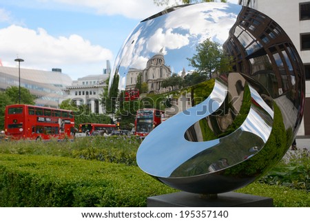 London, UK - May 25, 2014: St. Paul\'s Cathedral is reflected in a sculpture on May 25, 2014. Red London buses queue down Carter Lane beyond.